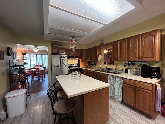 kitchen featuring ceiling fan, light hardwood / wood-style floors, a breakfast bar, a kitchen island, and appliances with stainless steel finishes