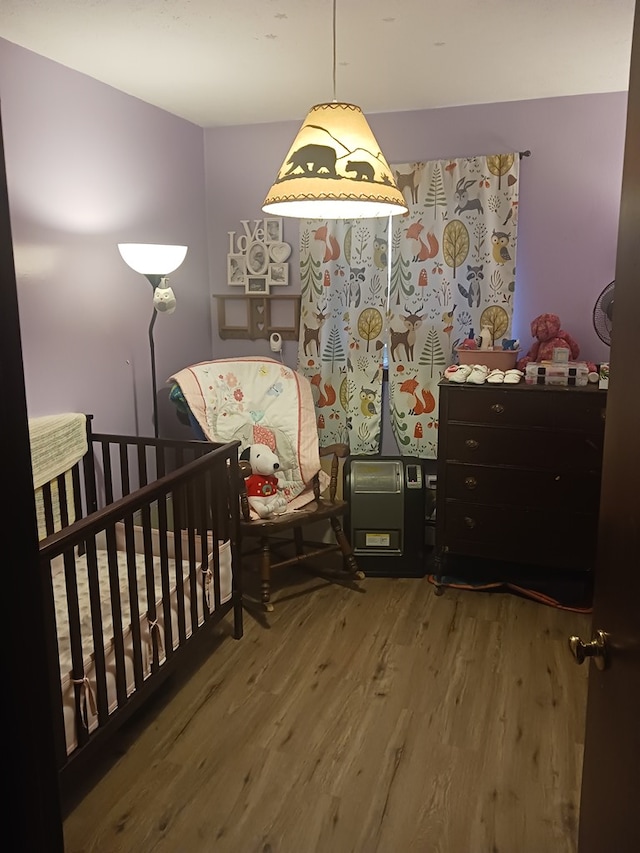 bedroom with wood-type flooring and a crib