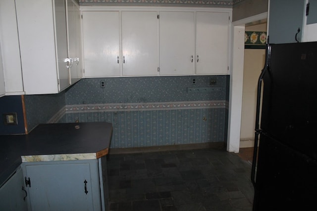 kitchen with white cabinetry and black fridge