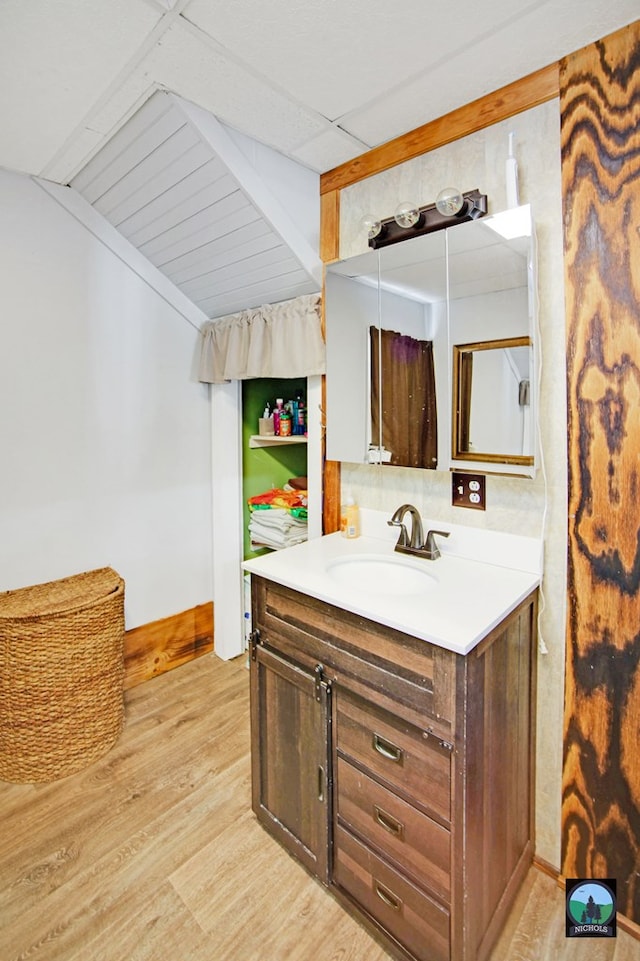 bathroom featuring hardwood / wood-style flooring, vanity, lofted ceiling with beams, and backsplash