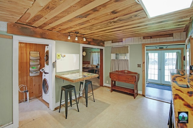 kitchen with french doors, rail lighting, stacked washing maching and dryer, wooden ceiling, and a breakfast bar area