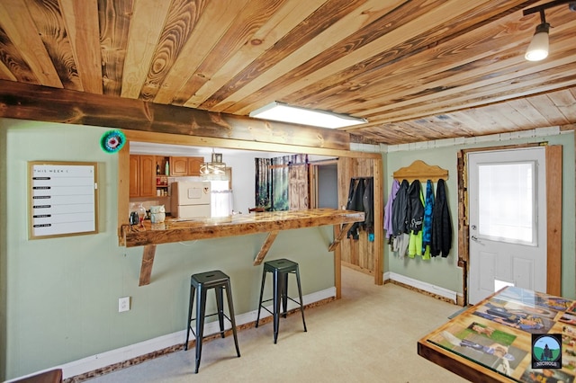 kitchen with a breakfast bar, white fridge, wood ceiling, and kitchen peninsula