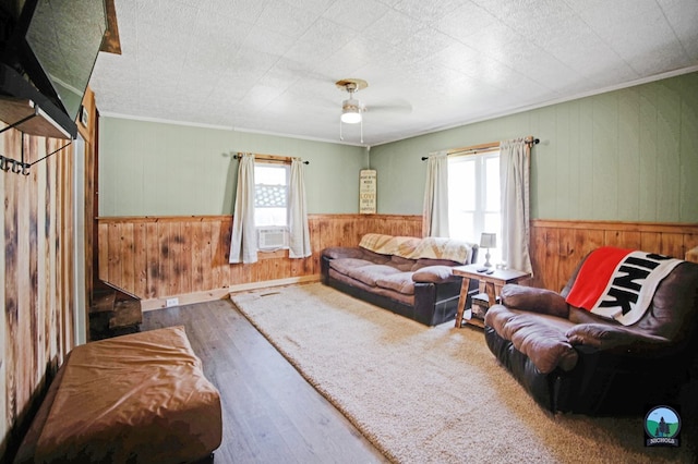 living room with ceiling fan, plenty of natural light, wood-type flooring, and wooden walls