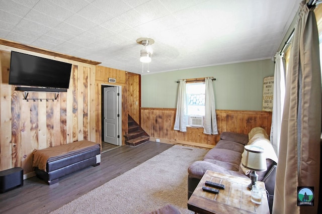 living room featuring hardwood / wood-style floors, cooling unit, crown molding, wooden walls, and ceiling fan