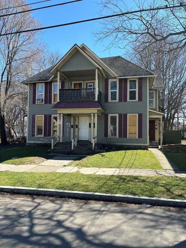 view of front of property featuring a balcony and a front lawn