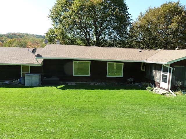 back of house with a sunroom and a lawn