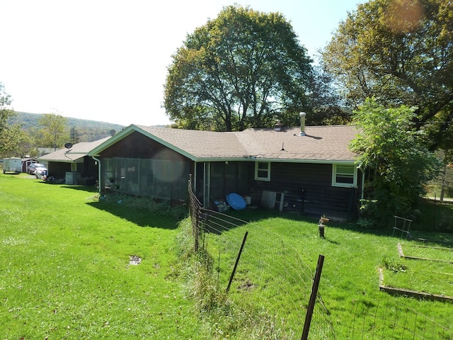 rear view of property featuring a lawn and a sunroom