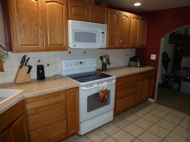 kitchen featuring light tile patterned flooring, backsplash, and white appliances