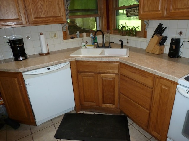 kitchen with dishwasher, sink, light tile patterned floors, and decorative backsplash