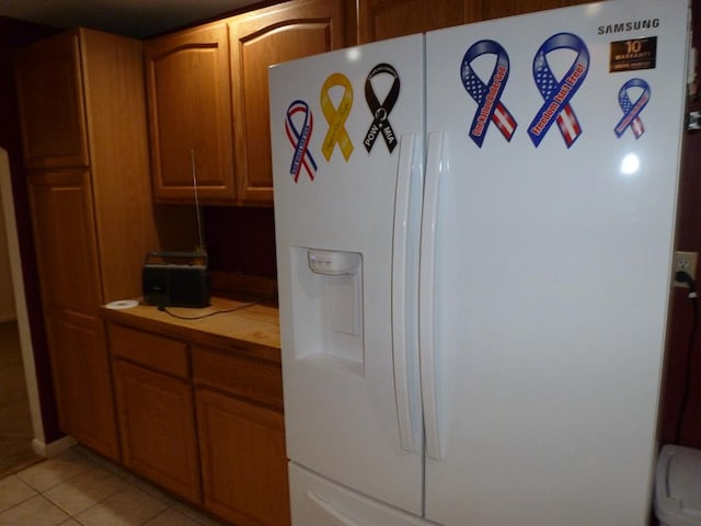 kitchen featuring tile counters, light tile patterned floors, and white refrigerator with ice dispenser