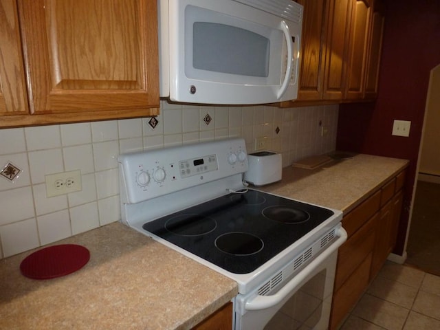 kitchen featuring tasteful backsplash, white appliances, and tile patterned floors