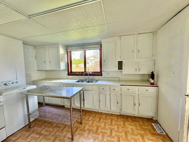 kitchen with white cabinetry, sink, washer / clothes dryer, and light parquet flooring