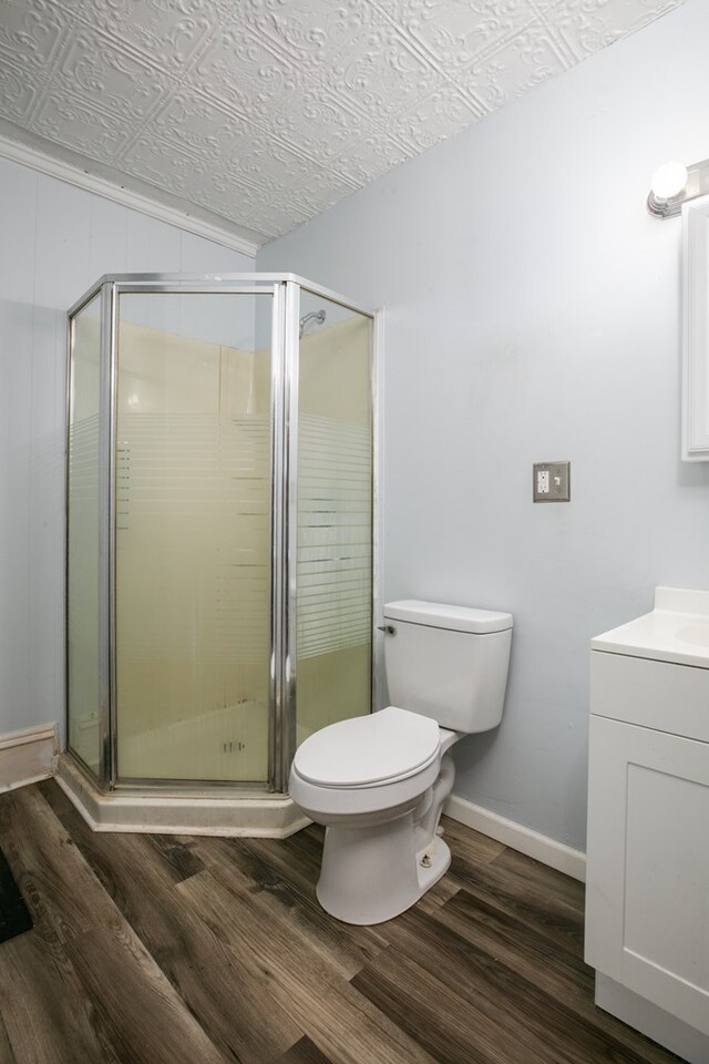 bathroom with toilet, wood-type flooring, vanity, and a shower with shower door