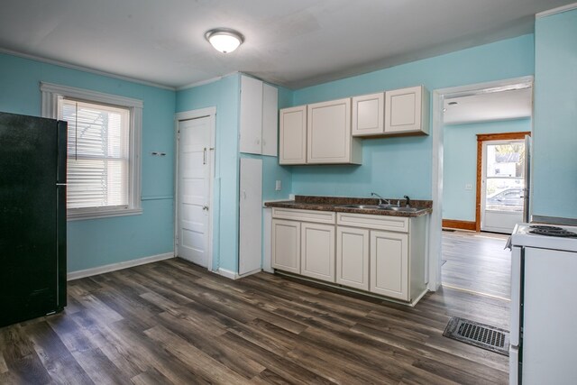 kitchen with black fridge, white cabinets, white gas range oven, and a wealth of natural light