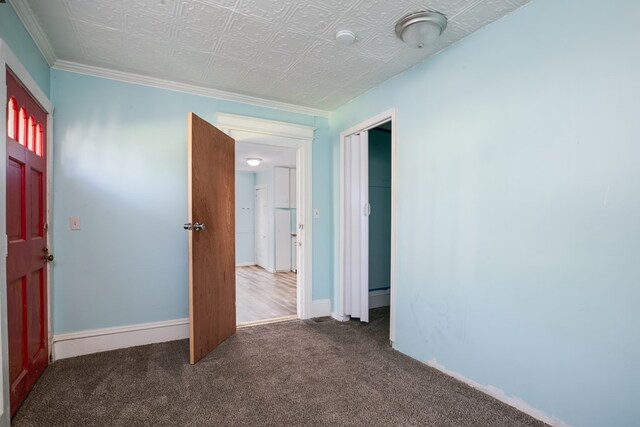 spare room featuring dark carpet and ornamental molding