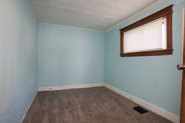 spare room featuring a textured ceiling, crown molding, and dark colored carpet