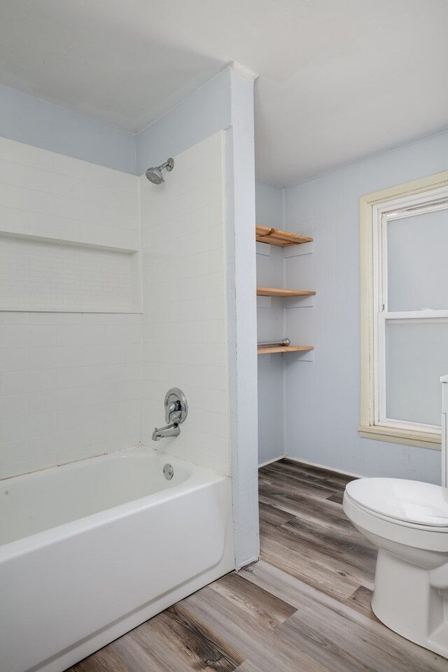 bathroom featuring toilet, tiled shower / bath combo, and hardwood / wood-style floors