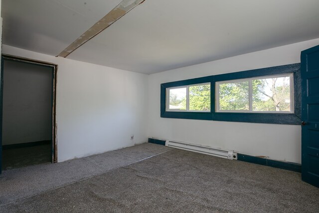 empty room with a baseboard heating unit, carpet, and plenty of natural light