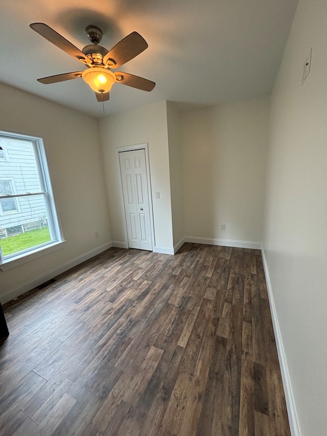 unfurnished bedroom with ceiling fan, dark hardwood / wood-style flooring, and a closet