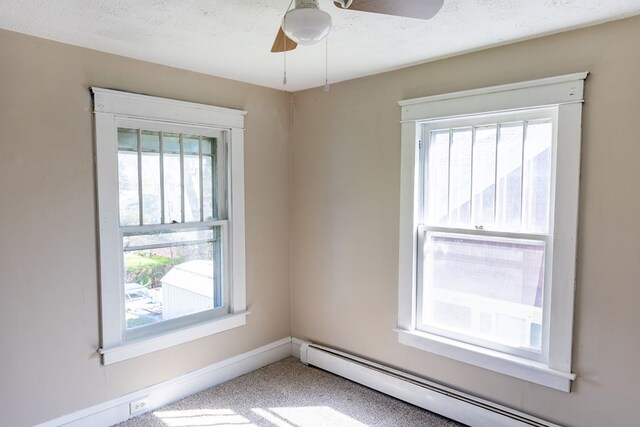 empty room with ceiling fan, carpet, a textured ceiling, and a baseboard heating unit