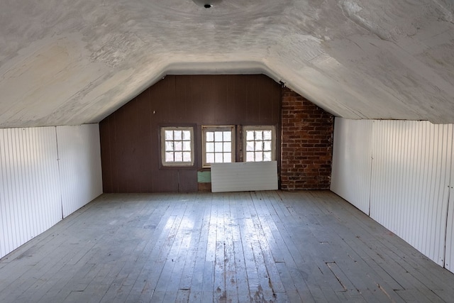 bonus room featuring light hardwood / wood-style flooring, vaulted ceiling, and wooden walls