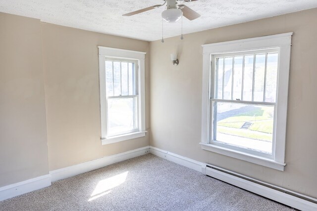 empty room featuring a textured ceiling, plenty of natural light, and baseboard heating