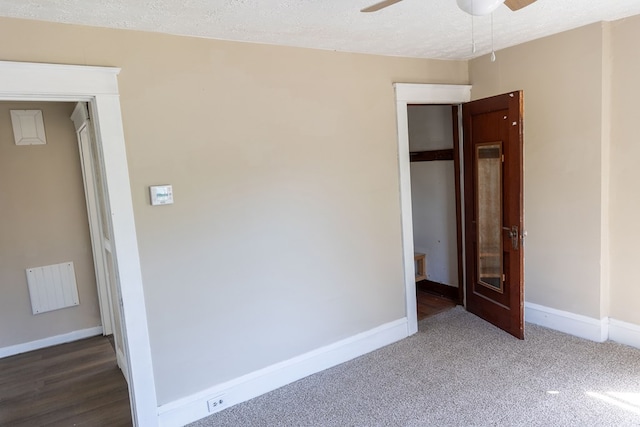 unfurnished bedroom featuring ceiling fan, dark hardwood / wood-style flooring, a textured ceiling, and a closet