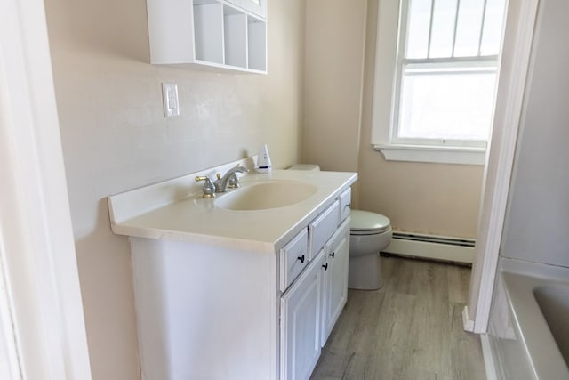 bathroom with a bathtub, vanity, a baseboard radiator, hardwood / wood-style flooring, and toilet