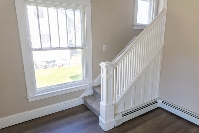 stairs with a wealth of natural light, a baseboard radiator, and hardwood / wood-style flooring