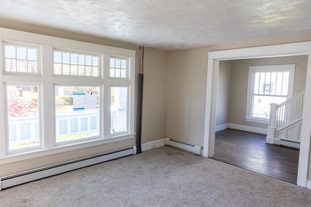 empty room featuring a baseboard radiator, plenty of natural light, and hardwood / wood-style flooring