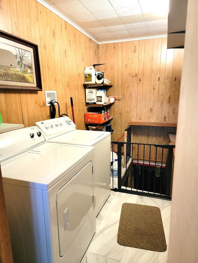 washroom with washing machine and dryer and wooden walls