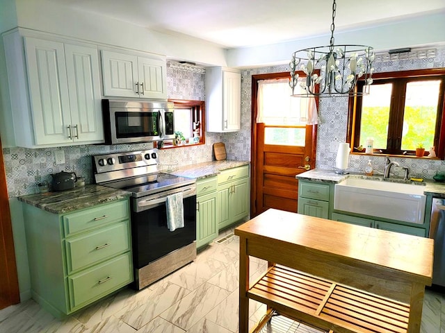 kitchen featuring decorative light fixtures, a healthy amount of sunlight, sink, and appliances with stainless steel finishes