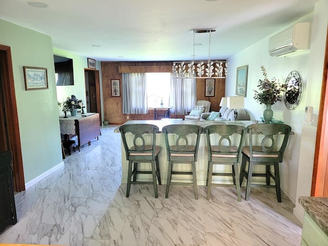 kitchen with a wall unit AC, a kitchen bar, and decorative light fixtures