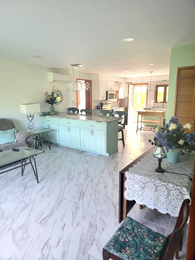 kitchen with kitchen peninsula, hanging light fixtures, a wall mounted AC, a kitchen bar, and white cabinetry