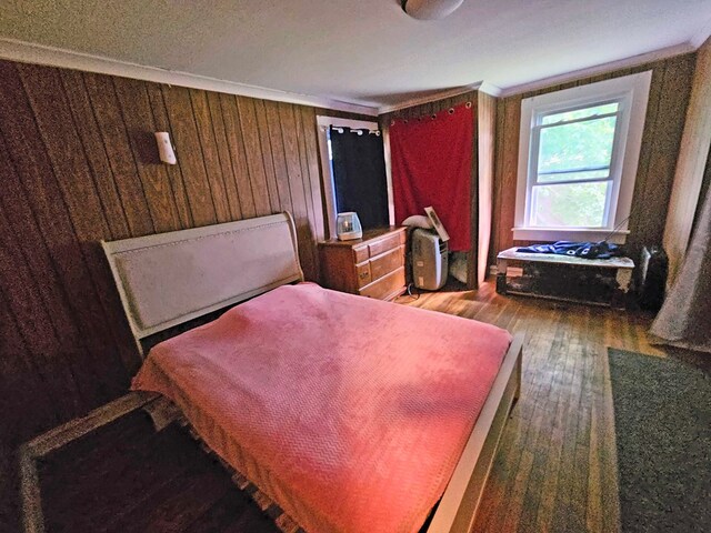 bedroom featuring dark hardwood / wood-style floors, ornamental molding, and wooden walls