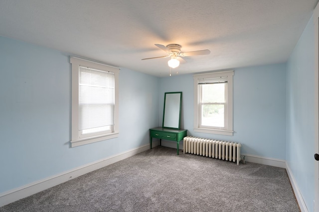 empty room featuring carpet, radiator heating unit, a textured ceiling, and a wealth of natural light