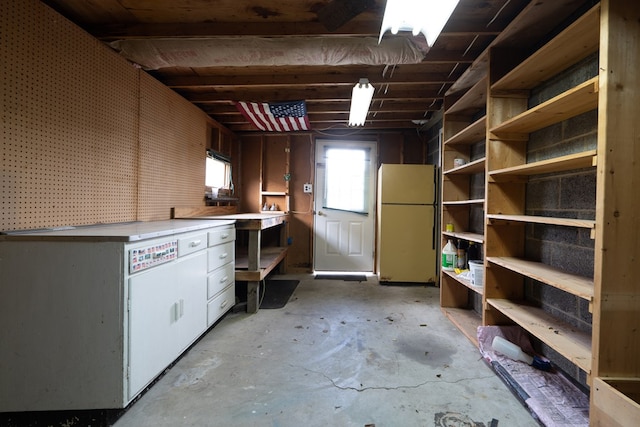 basement with a workshop area and white refrigerator