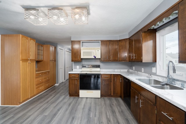 kitchen featuring light stone countertops, sink, hardwood / wood-style floors, a textured ceiling, and white appliances