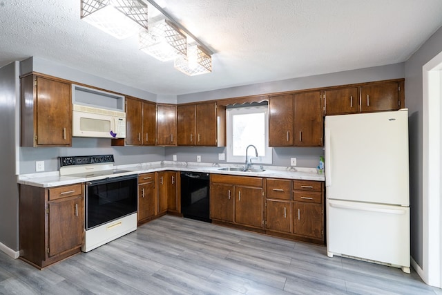 kitchen with a textured ceiling, white appliances, light hardwood / wood-style floors, and sink