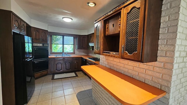 kitchen featuring sink, light tile patterned floors, kitchen peninsula, dark brown cabinets, and black appliances