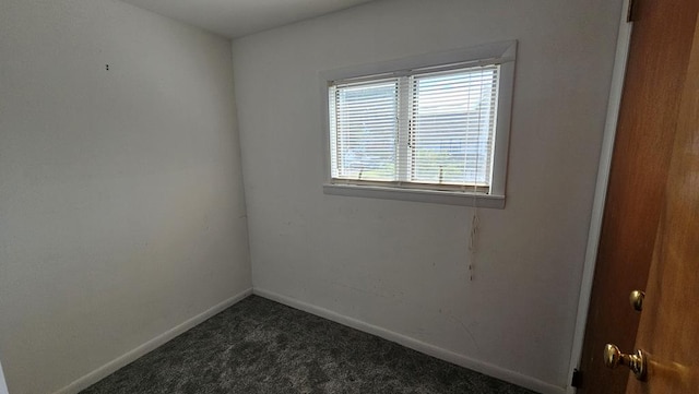 unfurnished room featuring dark carpet