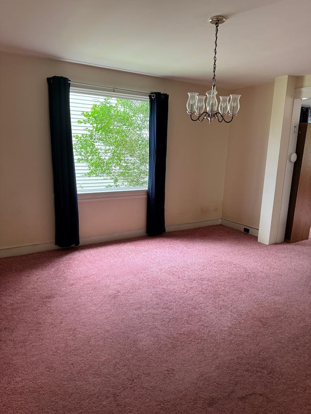 carpeted empty room with an inviting chandelier