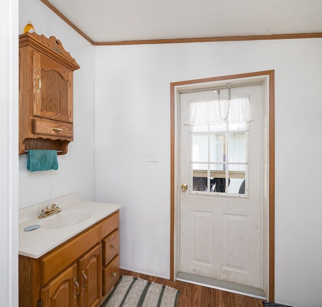 bathroom with lofted ceiling, vanity, wood-type flooring, and crown molding