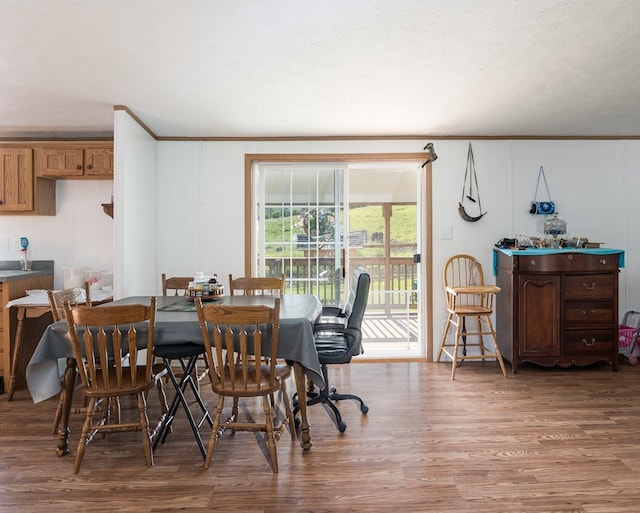 dining space featuring hardwood / wood-style floors, a textured ceiling, and ornamental molding