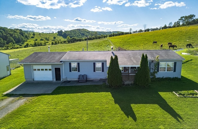 ranch-style house with a rural view, a garage, and a front lawn