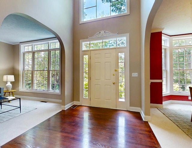 entrance foyer featuring dark wood-type flooring, ornamental molding, and a high ceiling