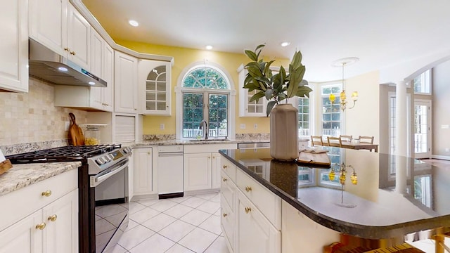 kitchen with stainless steel gas range, sink, a breakfast bar area, decorative light fixtures, and white cabinets