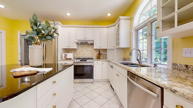 kitchen with sink, light tile patterned floors, appliances with stainless steel finishes, light stone countertops, and white cabinets