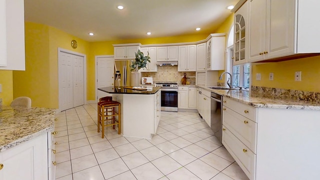 kitchen featuring white cabinetry, appliances with stainless steel finishes, a center island, and a kitchen breakfast bar