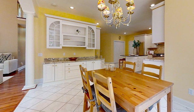 tiled dining room with decorative columns and a notable chandelier